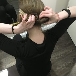 Einfache Frisuren für Anfänger Frau die ihr Haar am Hinterkopf hochsteckt